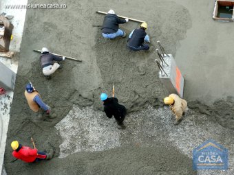 Muncitori care toarna si niveleaza beton