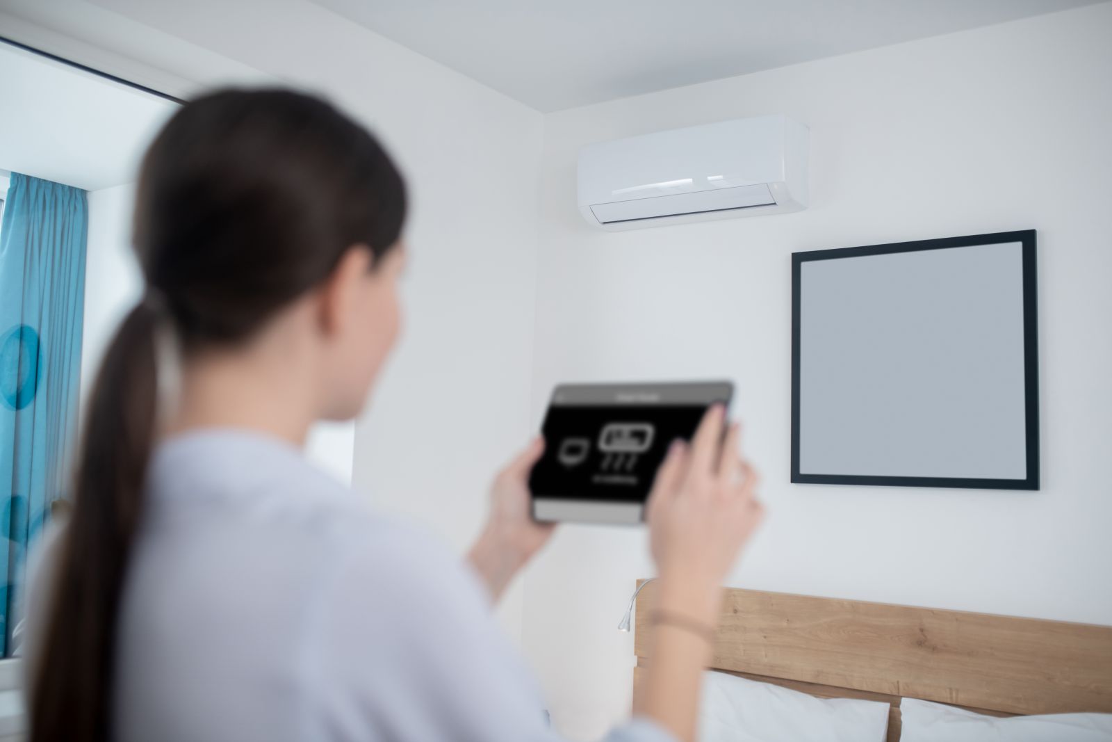 Femeie care controlează de pe tabletă un aparat de aer condiționat modern