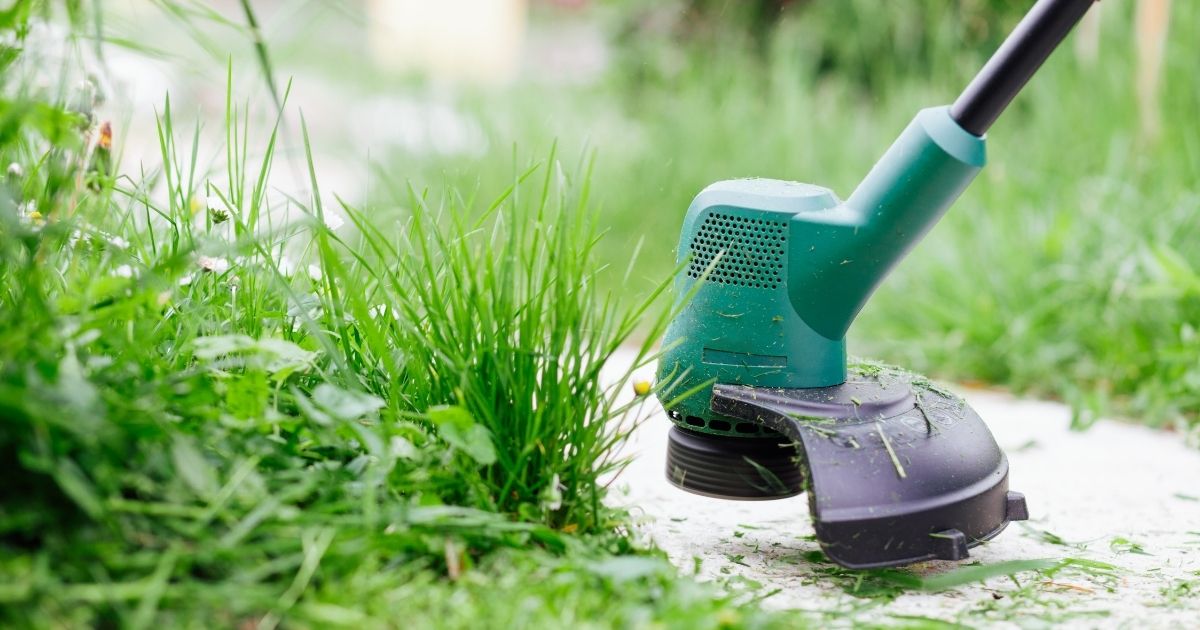 Trimmer electric folosit pentru tunderea ierbii pe marginea unei alei, cu fir potrivit pentru mașini de grădinărit.