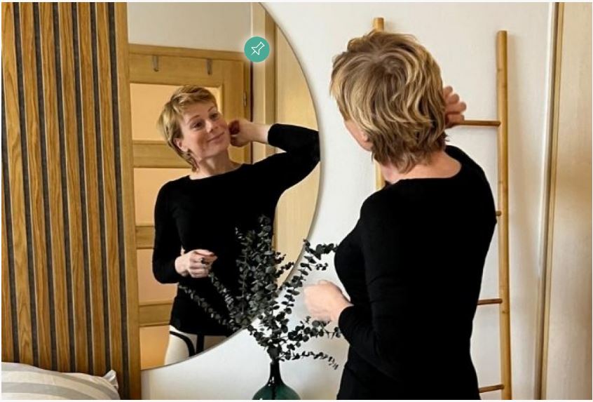 Oglindă decorativă rotundă amplasată într-un living modern, folosită pentru a amplifica lumina naturală și a mări vizual spațiul.