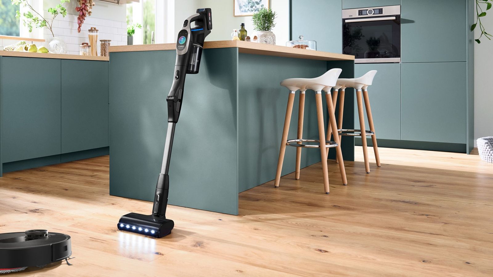 Aspirator robot smart Bosch și aspirator vertical într-o bucătărie modernă, ilustrând soluții inteligente pentru curățenia eficientă a locuinței.