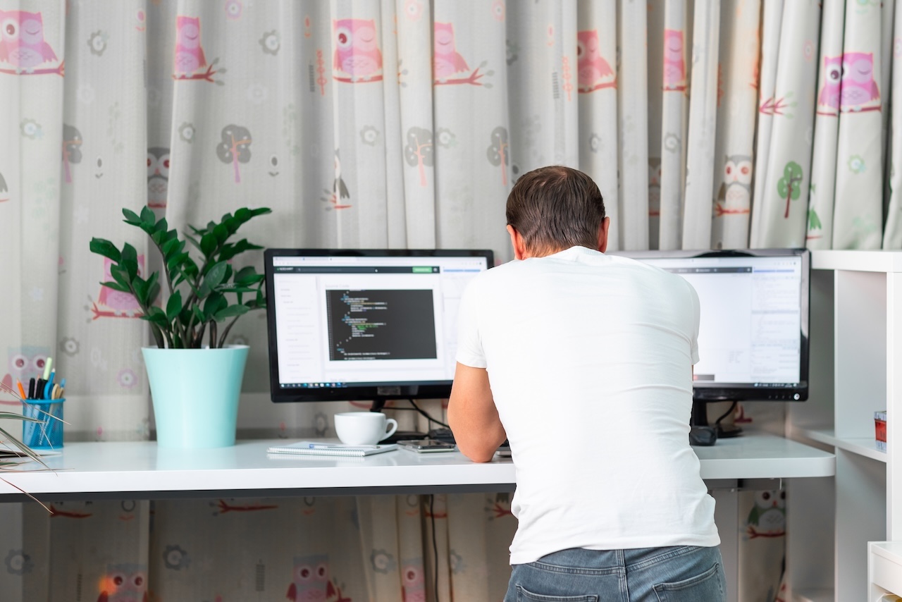 Persoană lucrând la birou reglabil pe înălțime, într-un spațiu luminos și ergonomic