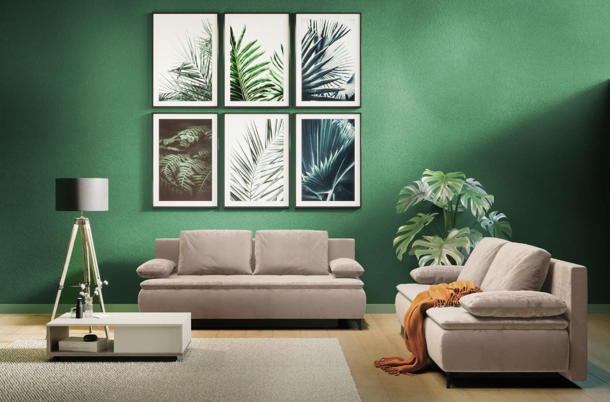 Canapea mare bej într-un living mic, cu perete verde și decorațiuni naturale – exemplu de echilibru între confort și design