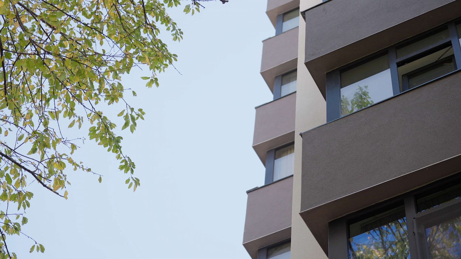 Fațadă modernă de bloc cu ferestre PVC Barrier, exemplu de tâmplărie eficientă energetic, reflectând lumina naturală.