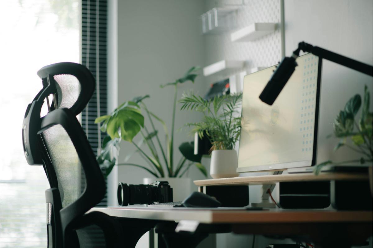 Birou modern amenajat pe balconul unui apartament, cu monitor, plante și scaun ergonomic, proiect finanțabil prin credit online.