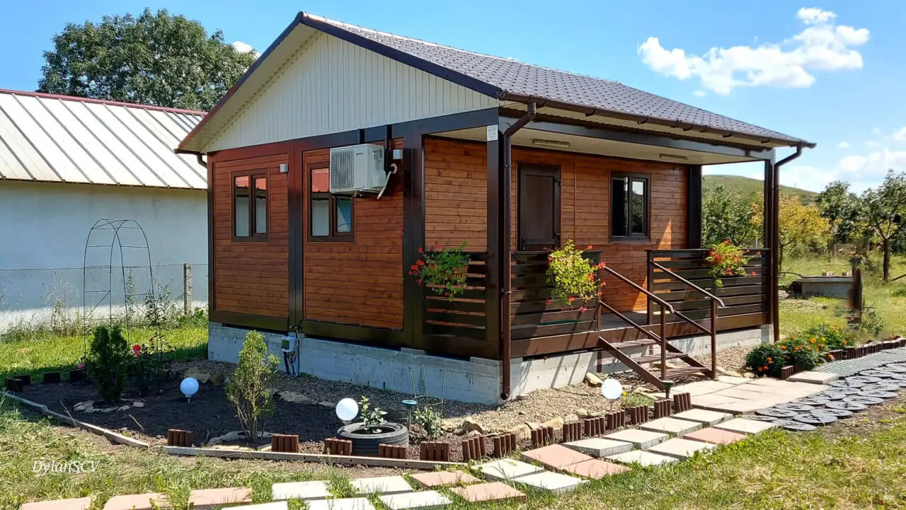 Casă modulară din containere finisată la cheie, cu terasă și fațadă decorativă din lemn, exemplu de locuință eficientă și rapid de montat.