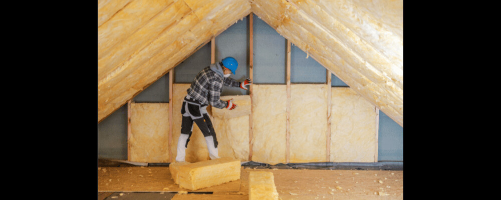 Meșter montează vată bazaltică pentru izolarea termică a podului, soluție eficientă pentru reducerea pierderilor de căldură iarna.