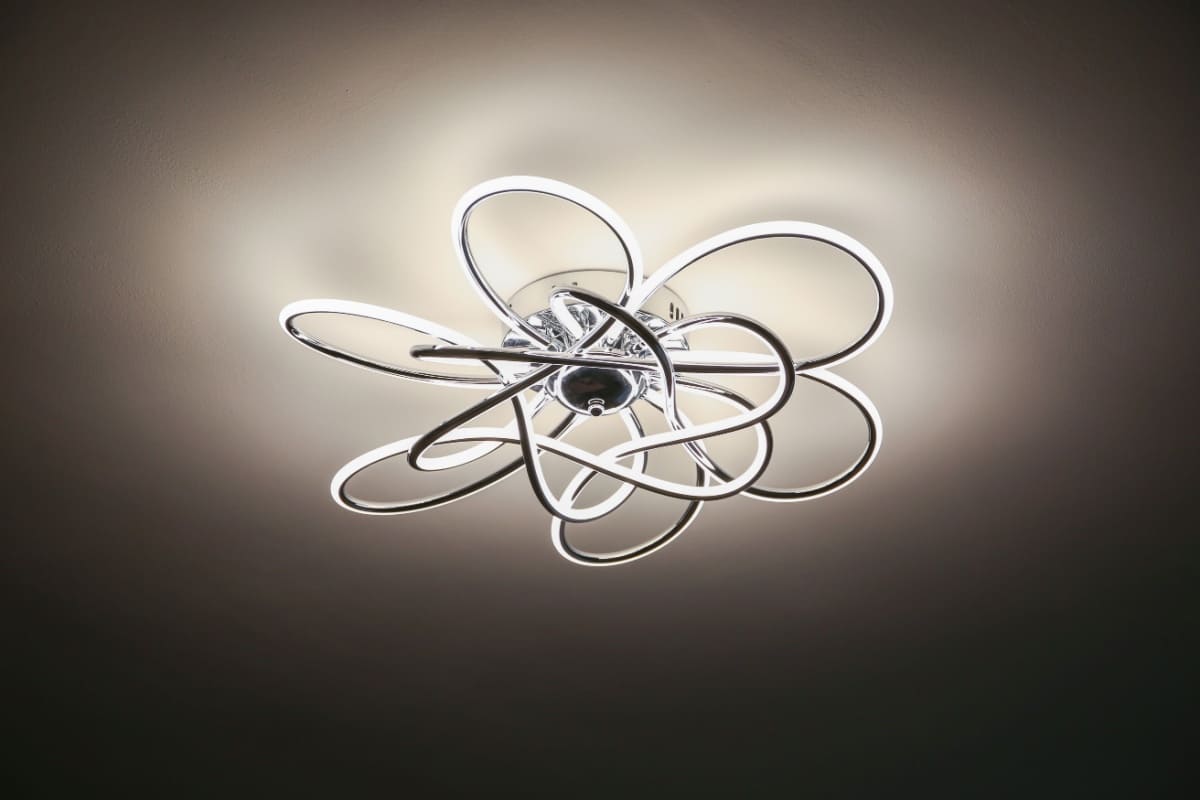 Lustră LED cu formă sculpturală, suspendată într-un living modern, iluminând armonios spațiul.