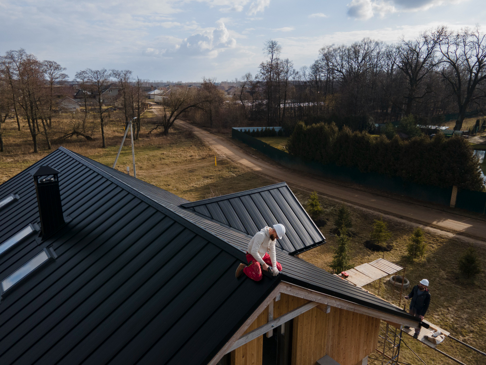 Montaj de acoperiș din tablă fălțuită pe o casă modernă, cu panouri metalice negre și sistem de prindere ascuns.