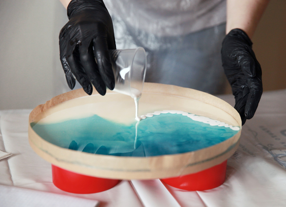 Turnare de rasina epoxidica colorata intr-o forma pentru realizarea unui obiect decorativ cu efect de apa.