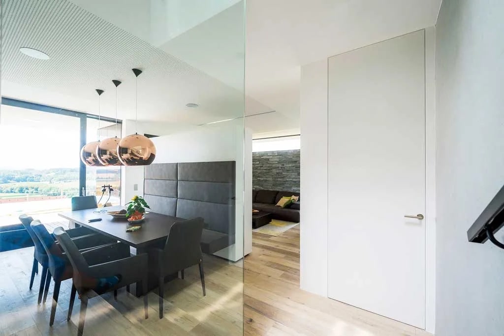 Ușă filomuro albă cu toc invizibil, integrată într-un interior modern, cu linii perfect coplanare.